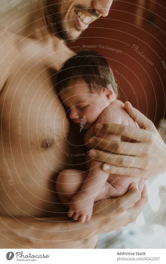 Anonymer hispanischer Mann ohne Hemd, der ein süßes Baby im Schlafzimmer umarmt neugeboren Umarmen Vater Liebe Pflege Vaterschaft Zuneigung Zusammensein Angebot
