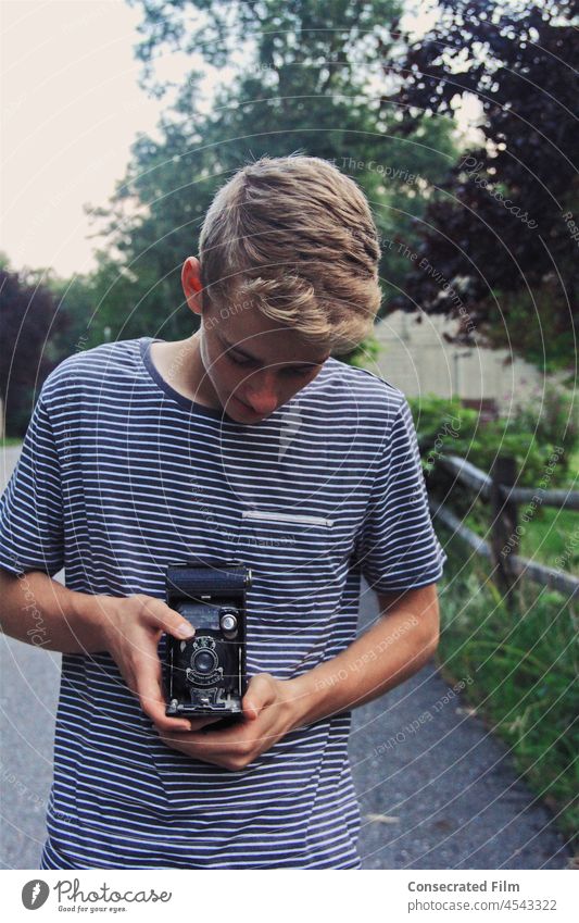 Junge auf dem Lande, der ein Foto mit einer alten Kamera macht kleiner Junge Fotokamera Fotografie reisen Abenteuer kreativ altehrwürdig Antiquitäten Bräune