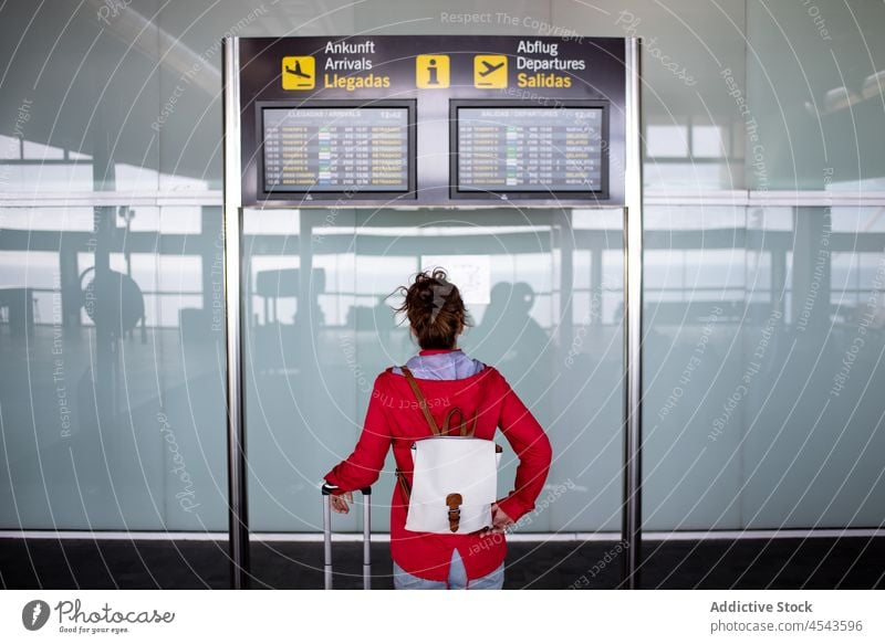 Nicht erkennbarer Reisender sitzt neben dem Fahrplan im Flughafen Frau Ausflug modern Terminal Abheben Zeitplanung Schild Öffentlich Zeitgenosse Gepäck Tourist
