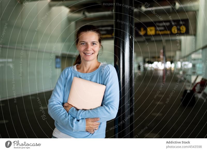 Fröhliche Frau mit Laptop im Flughafen Reisender Ausflug Terminal Abheben Öffentlich Passagier Zeitgenosse Tourist Infrastruktur modern Stil international Dame