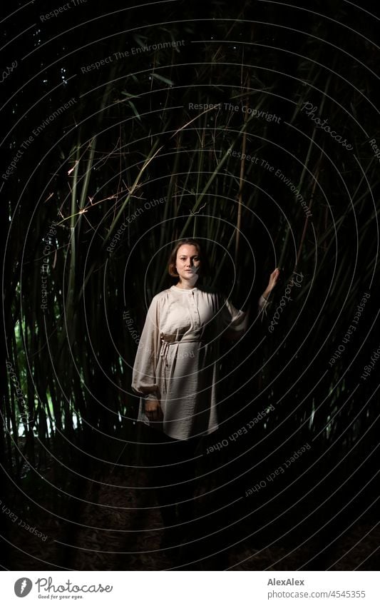 Portrait einer jungen Frau im Park in einem dunklen Bambuswald, Licht von der Seite beige grün Stimmung Frauengesicht Gesicht Freizeit selbstbewußt natürlich