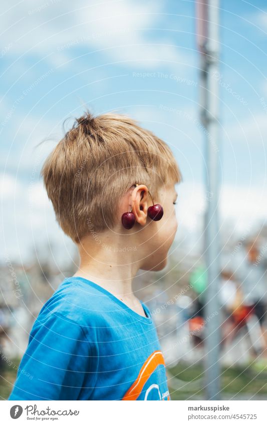 Kind mit Kirsche am Ohr Junge Kinderspiel Kindheit spass Spaß haben Spaßvogel spaßig Kirschen Ohrringe anhängen