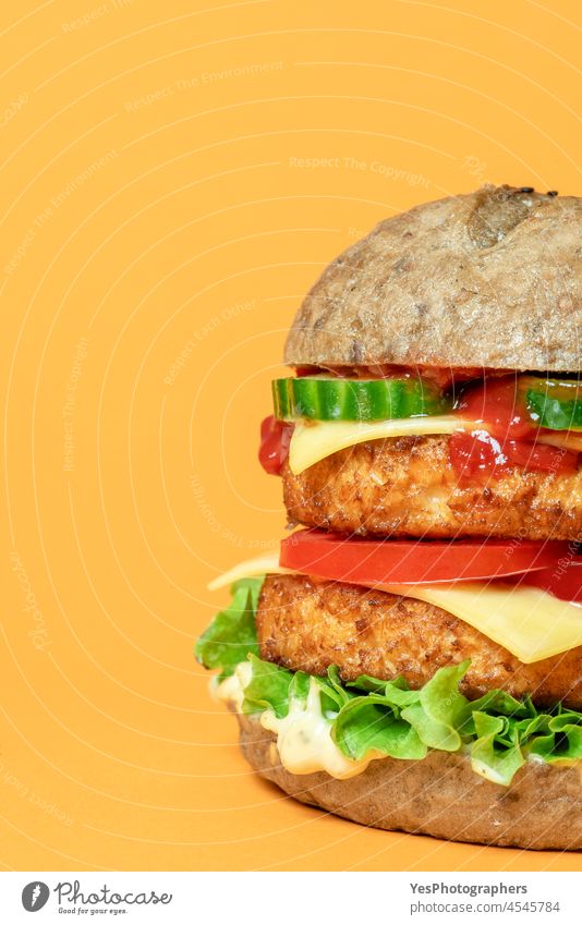 Veggie-Burger in Großaufnahme isoliert auf orangefarbenem Hintergrund. alternativ Brot Brötchen Käse Cheeseburger Nahaufnahme Farbe Konsumverhalten Küche lecker