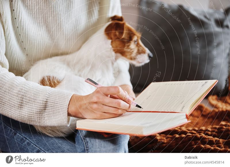 Frau schreibt Notizen in Notizbuch zu Hause Hund Notebook Tagebuch Plan Lifestyle gemütlich heimwärts ruhen sich[Akk] entspannen Büro Arbeitsplatz
