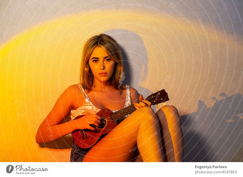 Niedliche, verträumte junge Frau, die zu Hause Ukulele und akustische Gitarre spielt. attraktiv heiter klassisch Konzert Bildung Emotion Behaarung Hand Glück