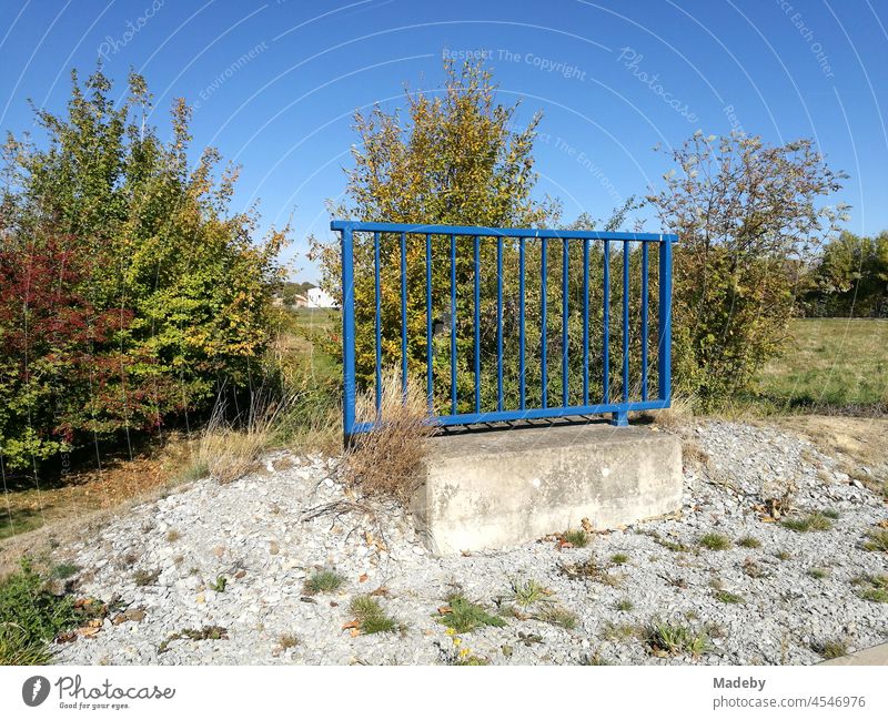 Schönes blaues Geländer aus Stahl mit Fundament aus Beton im unbebauten Nirgendwo vor blauem Himmel bei Sonnenschein in Oelde bei Warendorf im Münsterland in Westfalen