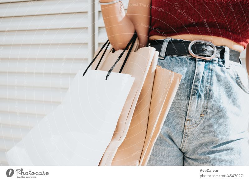 Elegante und moderne Frau steht auf der Straße in der Stadt und hält ein Bündel Einkaufstaschen. Close up Schuss der Frau Hand. Lifestyle Konsumverhalten Thema.
