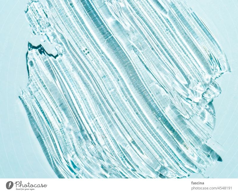 Transparentes kosmetisches Gel diagonale Abstriche auf blau Schliere Textur liquide Kosmetik Schmierfleck Hyaluronsäure übersichtlich Hintergrund Ästhetik