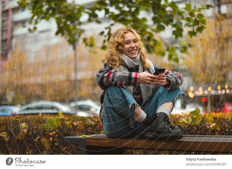 Junge Frau in der Stadt, die ihr Mobiltelefon überprüft eine Person Erwachsener schön lässig Mädchen Menschen Lifestyle urban Großstadt Straße attraktiv Porträt