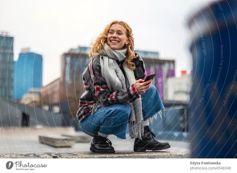 Lächelnde junge Frau in der Stadt, die ein Mobiltelefon hält eine Person Erwachsener schön lässig Mädchen Menschen Lifestyle urban Großstadt Straße attraktiv