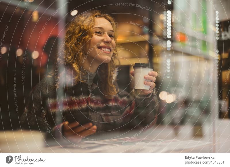 Lächelnde junge Frau mit einer Tasse Kaffee hinter einem Fenster in einem Cafe eine Person Erwachsener schön lässig Mädchen Menschen Lifestyle urban Großstadt