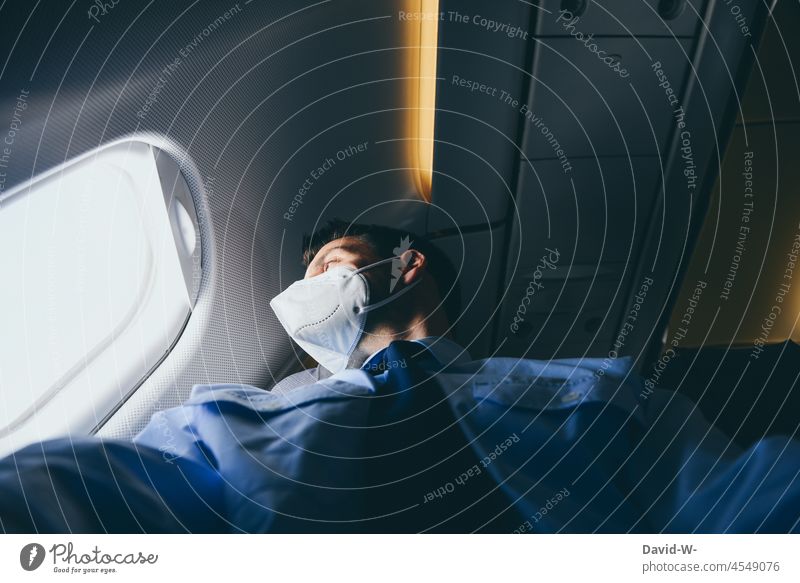 reisen - Mit Maske im Flugzeug in Zeiten der Pandemie Mann Atemschutzmaske Maskenpflicht urlaub fliegen Schützen Tourist Fenster geschäftlich Geschäftsmann