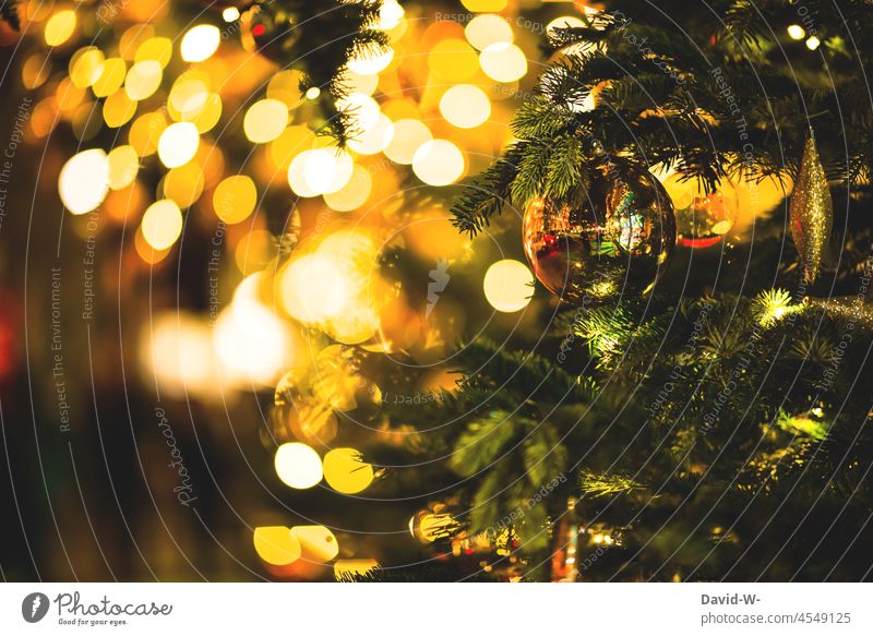 Christbaumkugel an einem Tannanbaum mit vielen leuchtenden Lichtern einer Lichterette Lichterkette Lichterketten Glanz Bokeh zauberhaft weihnachtlich