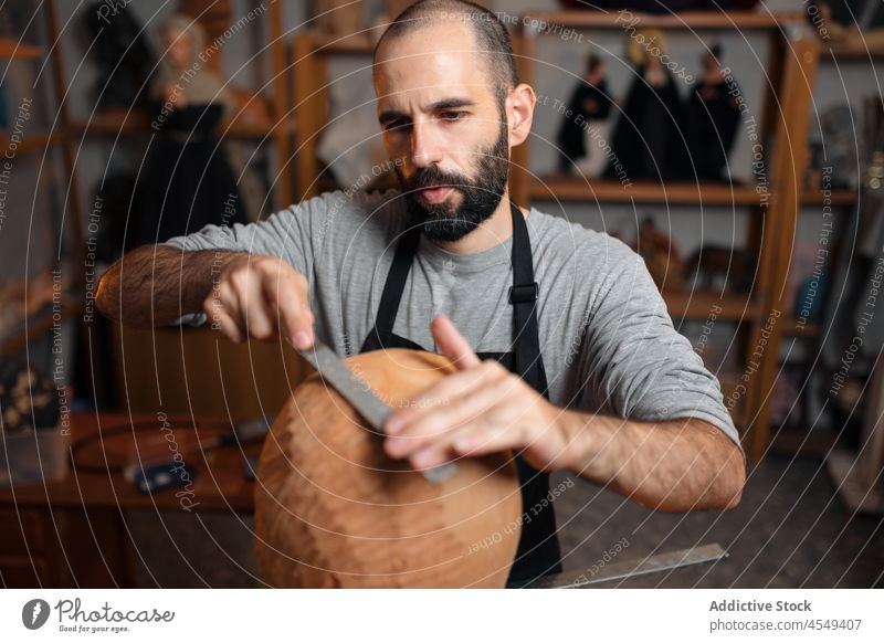 Seriöser Handwerker poliert Holzdetails Zimmerer polnisch raspeln Tischlerarbeit Werkstatt Handarbeit Holzarbeiten Instrument Form professionell Arbeitsplatz