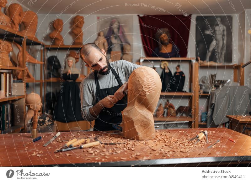 Konzentrierter Handwerker, der mit einem Meißel ein hölzernes Detail formt Zimmerer Beitel Form Holz Tischlerarbeit Werkstatt Handarbeit Holzarbeiten Instrument