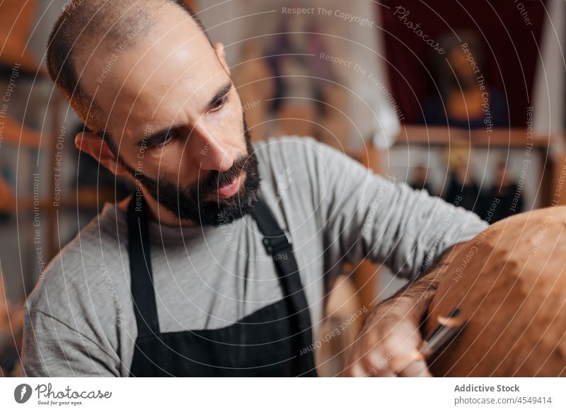 Konzentrierter Handwerker, der mit einem Meißel ein hölzernes Detail formt Zimmerer Beitel Form Holz Tischlerarbeit Werkstatt Handarbeit Holzarbeiten Instrument