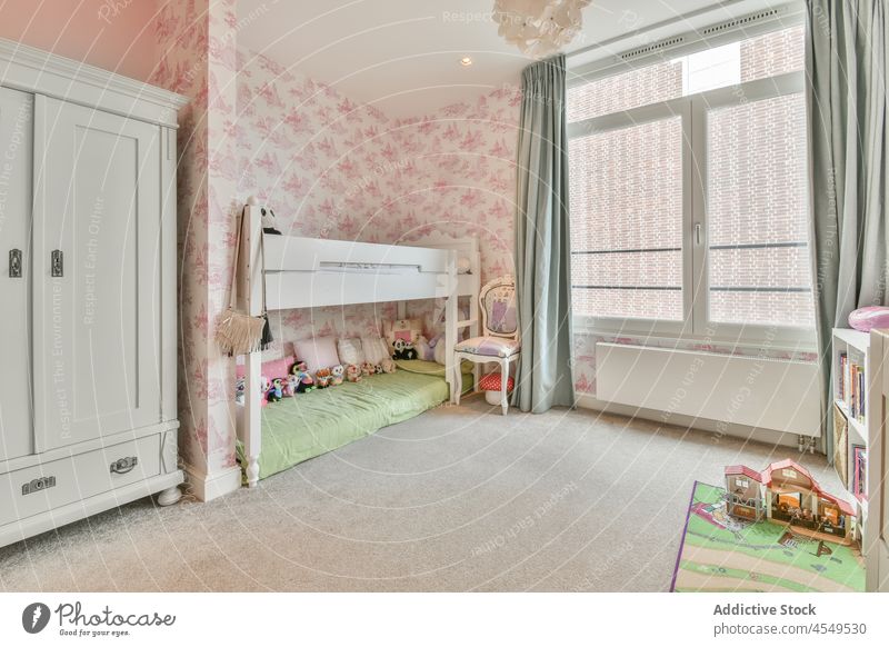 Interieur eines Kinderzimmers mit rosa Wänden und Holzmöbeln Schlafzimmer Mädchen Appartement Design wohnbedingt Bett Fenster Kleiderschrank Möbel flach Schrank