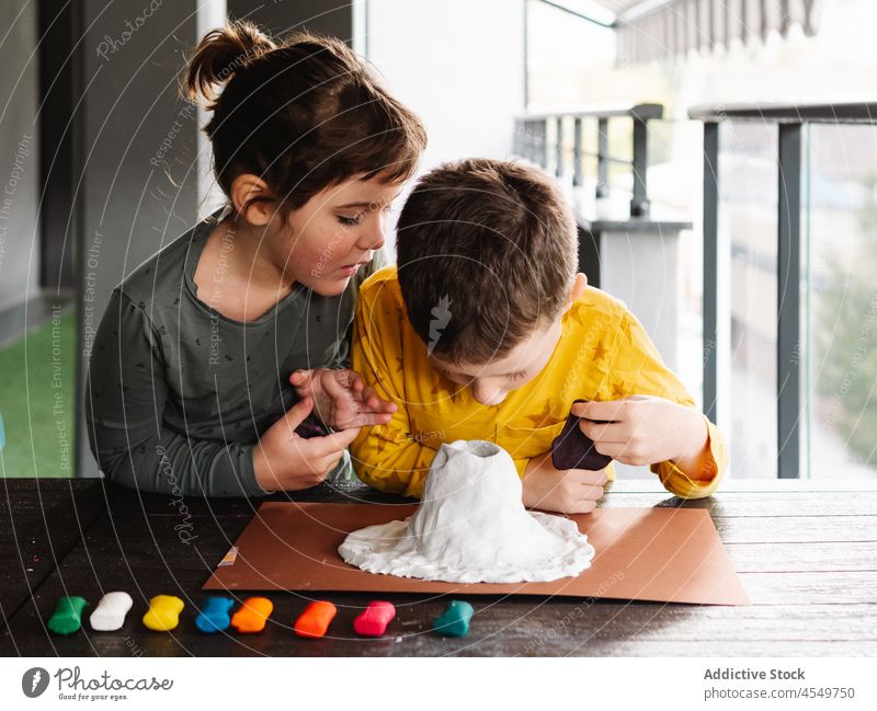 Konzentrierte Kinder formen Knetmasse und erschaffen eine Vulkanfigur spielen Knetgummi Figur handgefertigt Kindheit achtsam Bruder Schwester Schimmelpilze