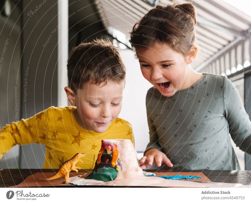 Erstaunte Kinder spielen mit Dinosaurierspielzeug und Knetvulkan Knetgummi Vulkan erstaunt aufgeregt wow Zusammensein Bruder Schwester Erstaunen bezaubernd