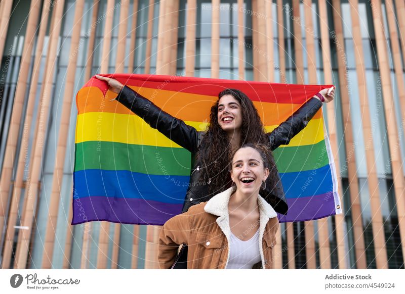 Glückliche homosexuelle Frauen mit LGBT-Flagge Paar lgbt Homosexualität Fahne Regenbogen Partnerschaft unkonventionell lesbisch gleich Solidarität Bonden