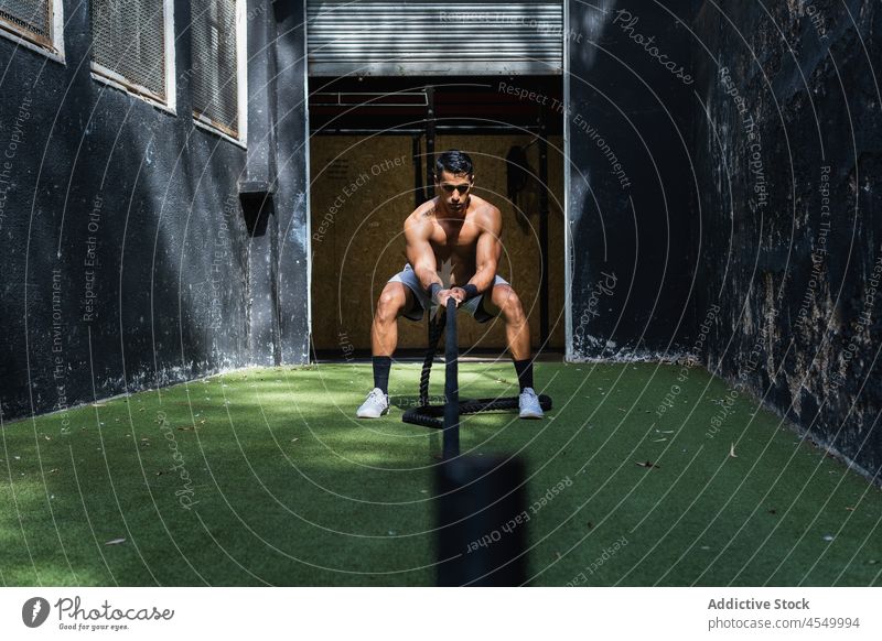 Muskulöser hispanischer Sportler, der einen Schlitten zieht Gewicht ziehen Kraftdreikampf Training Fitnessstudio Übung sportlich Gesunder Lebensstil