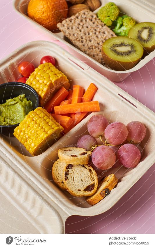 Geöffnete Behälter mit gesunden Snacks auf dem Tisch Lunch-Box Gesundheit Diät Ernährung Gemüse Frucht Kiwi Traube Walnussholz Cracker Beeren Lebensmittel