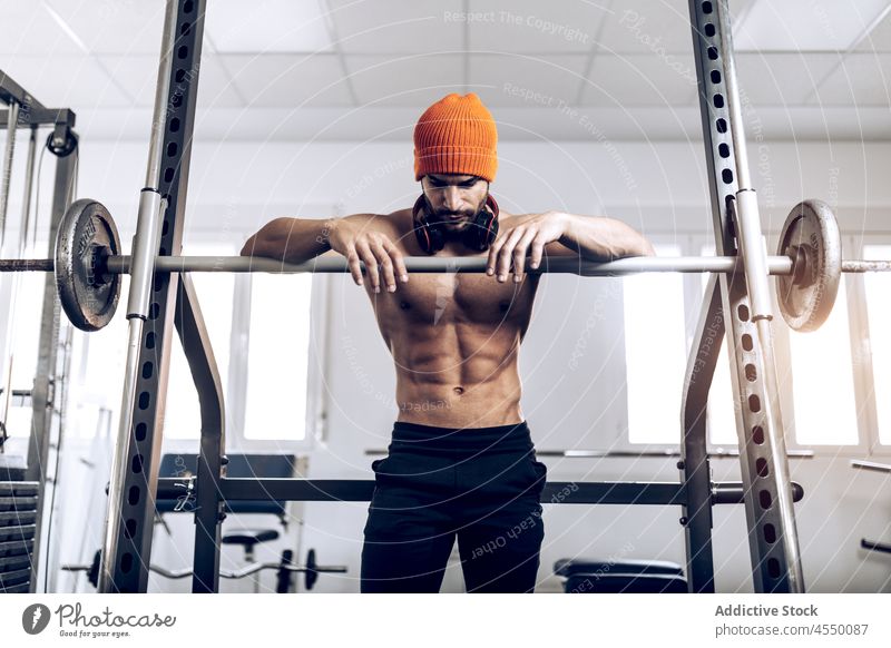 Muskulöser ethnischer Mann stützt sich auf eine Langhantel Athlet müde Wiederherstellung Curl-Hantel Muskel Pause Training Sport stark männlich Sportler Übung