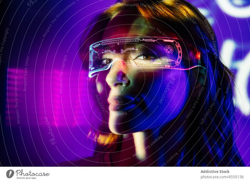 Frau in Neonlichtern mit Led-Brille futuristisch Metaversum Accessoire Augmented Reality Unschärfe Videospiel Kopfschuss hell modern Gerät Zeitgenosse cool