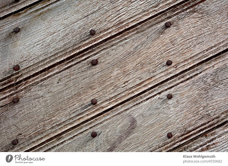 Detail einer kunstvollen, alten, verwitterten Holztür mit Nagelreihen aus rostigen Nägeln Tür Holzplatte Handwerk Rost diagonal Zierde verziert Sicherheit