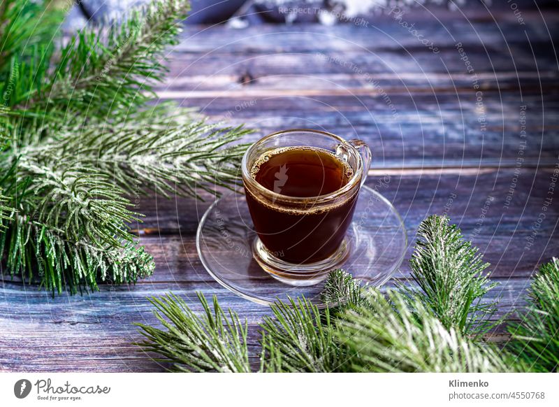 Eine Tasse aromatischen Kaffee mit braunem Zucker, Weihnachtsschmuck, Zweige eines Weihnachtsbaums. Urlaub Konzept Neujahr. Auf einem hölzernen Hintergrund.