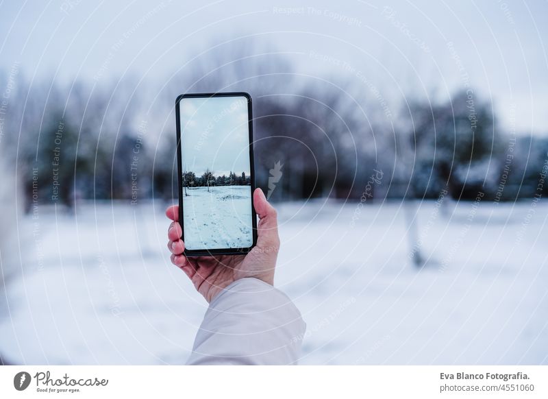 unerkennbare Frau, die ein Foto mit dem Handy in einer verschneiten Landschaft während der Wintersaison macht. Bild Schnee Bildschirm Gerät Fotograf kalt Mantel