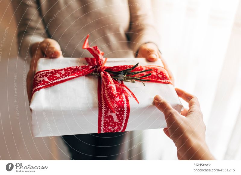 Frau gibt Weihnachtsgeschenk-Box mit roten gedruckten Band. Weihnachten und Neujahr Geschenk, Winterurlaub. 2022 Ornament fröhlich präsentieren Jahr neu Kasten