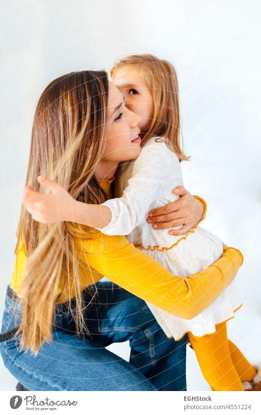 Business-Mutter, die ihre Tochter umarmt, auf weißem Hintergrund. Junge hispanische Frau. Mutter und Tochter Konzept. Mama Arbeit Umarmung Kleinkind umarmend