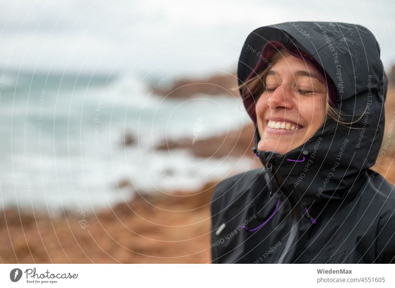 Freude im Herbststurm am Meer Regen Wind Sturm lachen Regenjacke Küste Felsen Junge Frau Glück