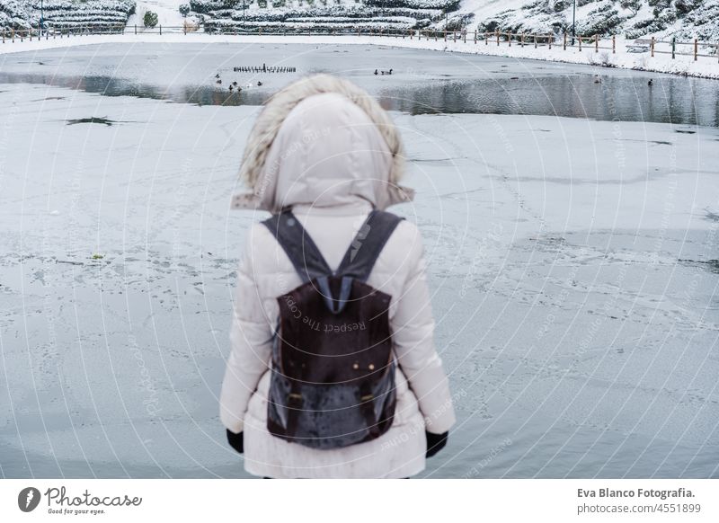 Rückenansicht einer Backpackerin vor einem zugefrorenen See in der Stadt. Lifestyle im Winter in der Stadt Frau Frost Pier Schnee Dock Großstadt Rucksack