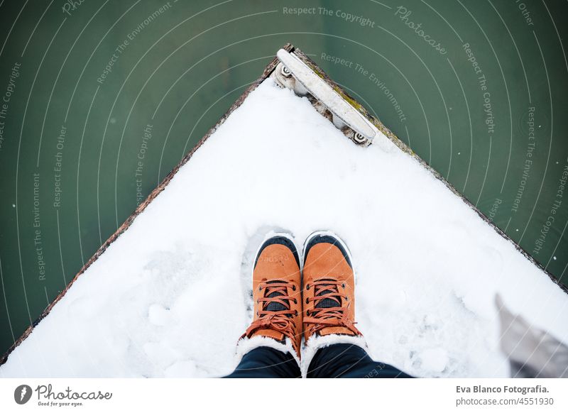 Ansicht von oben von unerkennbaren weiblichen Füße Stiefel stehen auf verschneiten Pier von gefrorenen See im Winter. Wandern Konzept unkenntlich Fuß Schnee