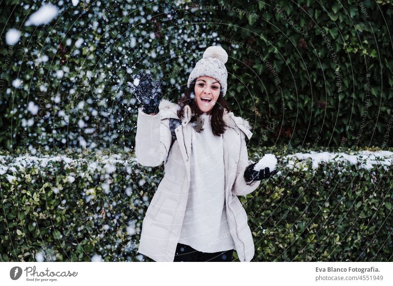verspielte kaukasische junge Frau spielt im Freien mit Schnee und Schneeflocken, wirft Schneeball in die Kamera, Spaß und Winter-Lifestyle Spielen Park