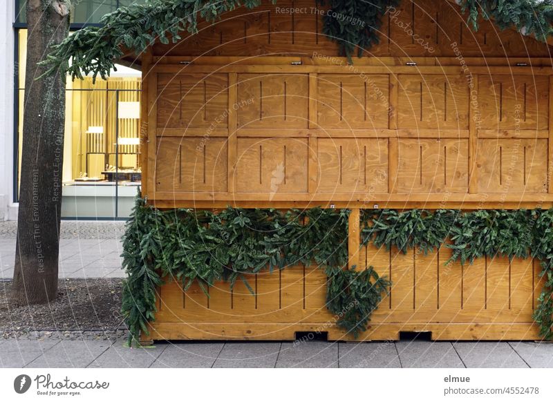 geschlossener weihnachtlicher Verkaufsstand aus Holz mit Tannengrün verziert in einer Einkaufsstraße der Innenstadt / Vorfreude / Corona-Verordnung