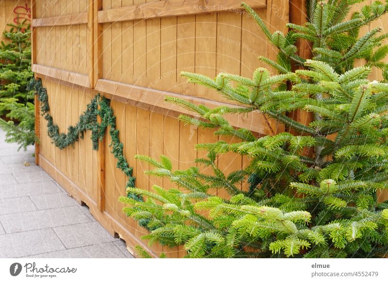 geschlossener weihnachtlicher Verkaufsstand aus Holz mit Weihnachtsbäumen und Tannengrün verziert / Vorfreude / Corona-Verordnung Weihnachtsstand Markthütte