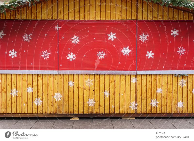 geschlossener weihnachtlicher Verkaufsstand aus Holz mit rotem Vorhang und aufgesprayten großen weißen Schneeflocken / Vorfreude / Corona-Verordnung