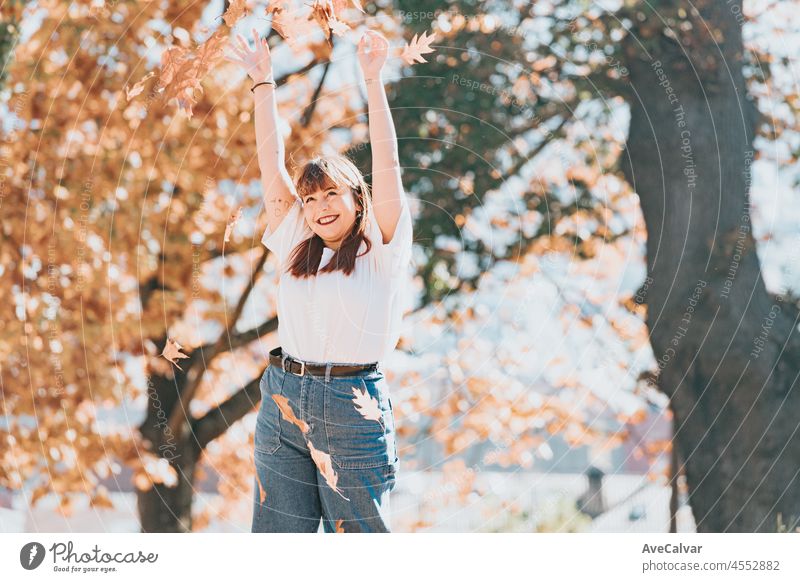 Glückliche junge Frau hat Spaß im Herbst forest.Woman Porträt. Happy Mädchen in weißem Hemd und blauen Jeans spielt mit Blatt, Blick auf die Kamera und lächelnd. Kopieren Raum.Porträt im Herbst Park.