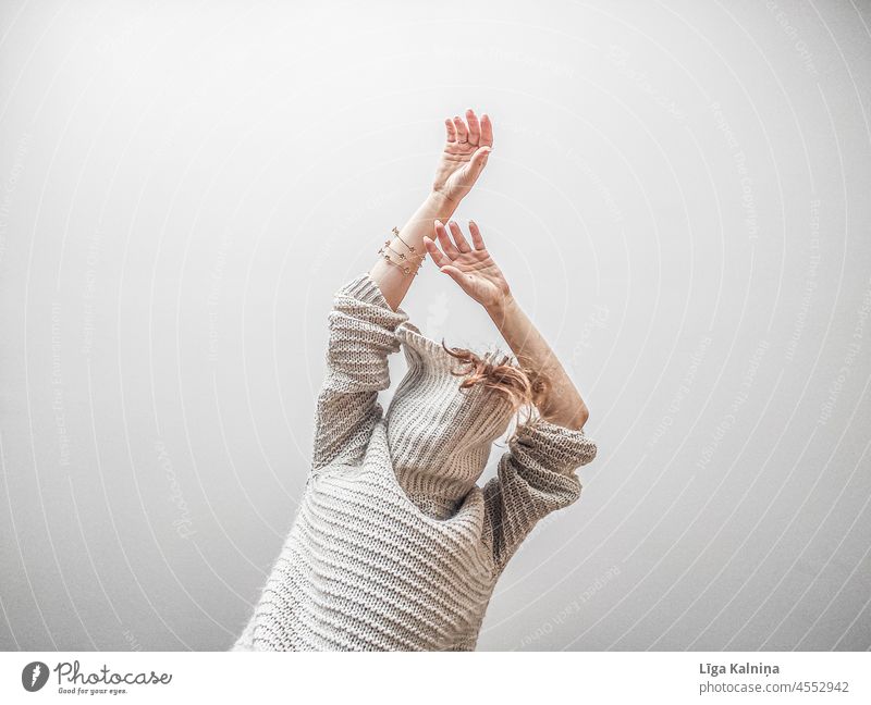 Anonyme Frau in einem großen übergroßen Pullover mit erhobenen Armen Strickpullover Wollpullover Wärme stricken Wolle gestrickt Innenaufnahme Bekleidung Mode