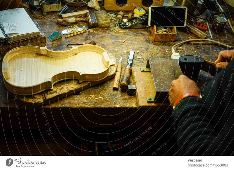 Geigenbauer an seinem Schreibtisch beim Biegen der Zargen einer Geige Zupfinstrumentenmacher Rippe Holz Cremona Körper Kunsthandwerker Handwerkskunst