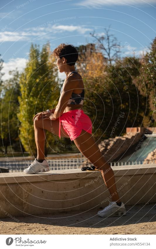 Sportliche junge hispanische Dame, die sich im Park die Beine vertritt Sportlerin Dehnung Aufwärmen Training Wellness Übung Vitalität Energie Frau Fitness