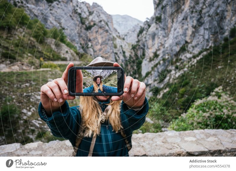 Verspielte Frau macht Selfie mit Smartphone während einer Wanderung in den Bergen Entdecker benutzend Zwinkern Grimasse Trekking Berge u. Gebirge Felsen