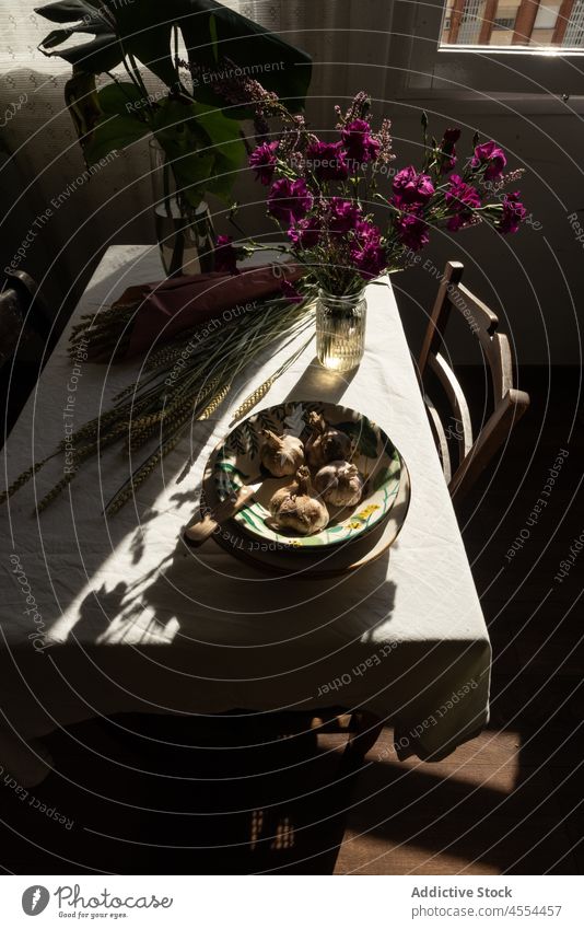 Schale mit Knoblauch in der Nähe eines Gras- und Blumenstraußes Schalen & Schüsseln Ernte Spitze Roggen Blütezeit rustikal Landschaft Gemüse Müsli Lebensmittel