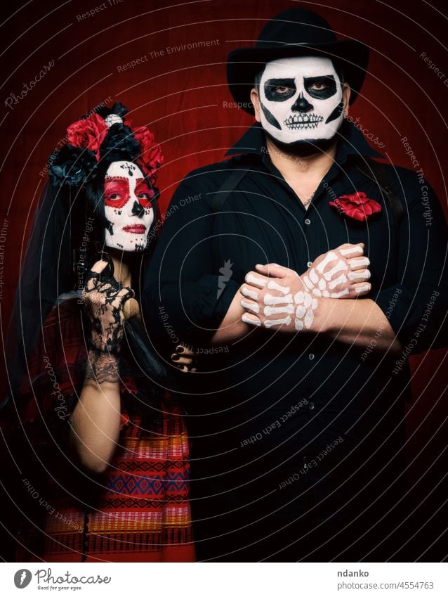 schöne Frau mit Zuckerschädel-Make-up und Blumenkranz auf dem Kopf und ein Skelettmann mit schwarzem Hut, der ein Gewehr hält Erwachsener Kunst Schönheit
