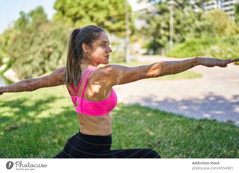 Frau macht Krieger Pose im Park Krieger-Pose Training Übung Asana Pilates Rasen üben Yoga Sportkleidung virabhadrasana Sportbekleidung Wohlbefinden aktiv passen