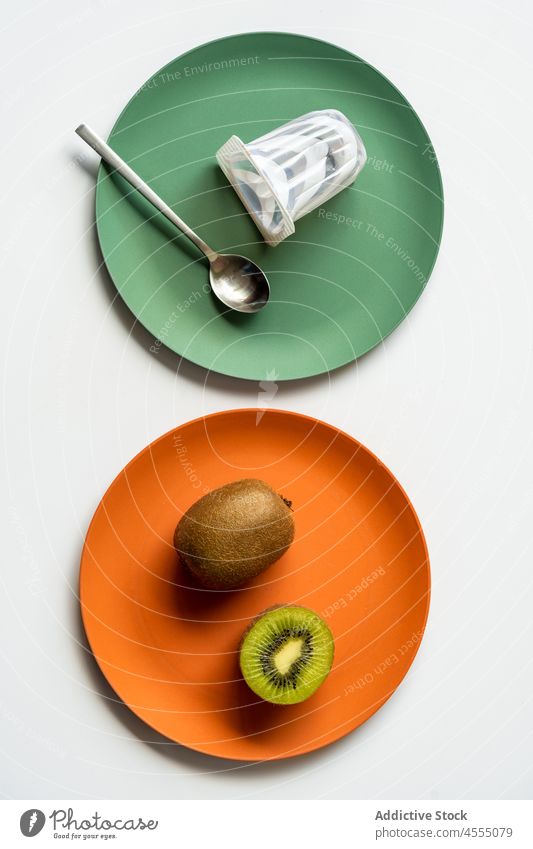 Reife gesunde Kiwi mit Joghurt und Löffel auf bunten Tellern serviert Frucht Vitamin frisch reif sehr wenige Keramik Tisch Gesundheit halbiert Lebensmittel