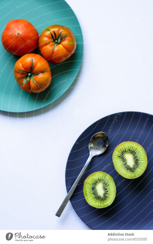 Reife Kiwi und Tomaten auf farbigen Keramiktellern auf dem Tisch Vitamin frisch Frucht Gemüse Gesundheit Lebensmittel natürlich Teller reif Veganer organisch